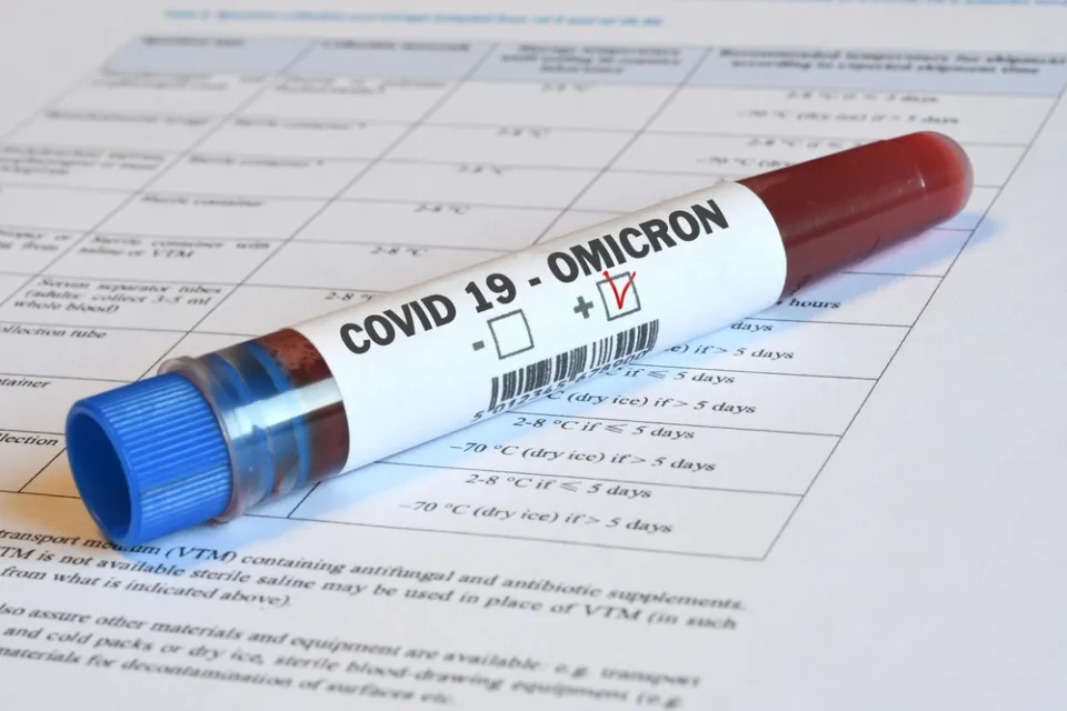 A vial of blood marked "Omicron" sits on top of paperwork indicating relevance to Covid-19.